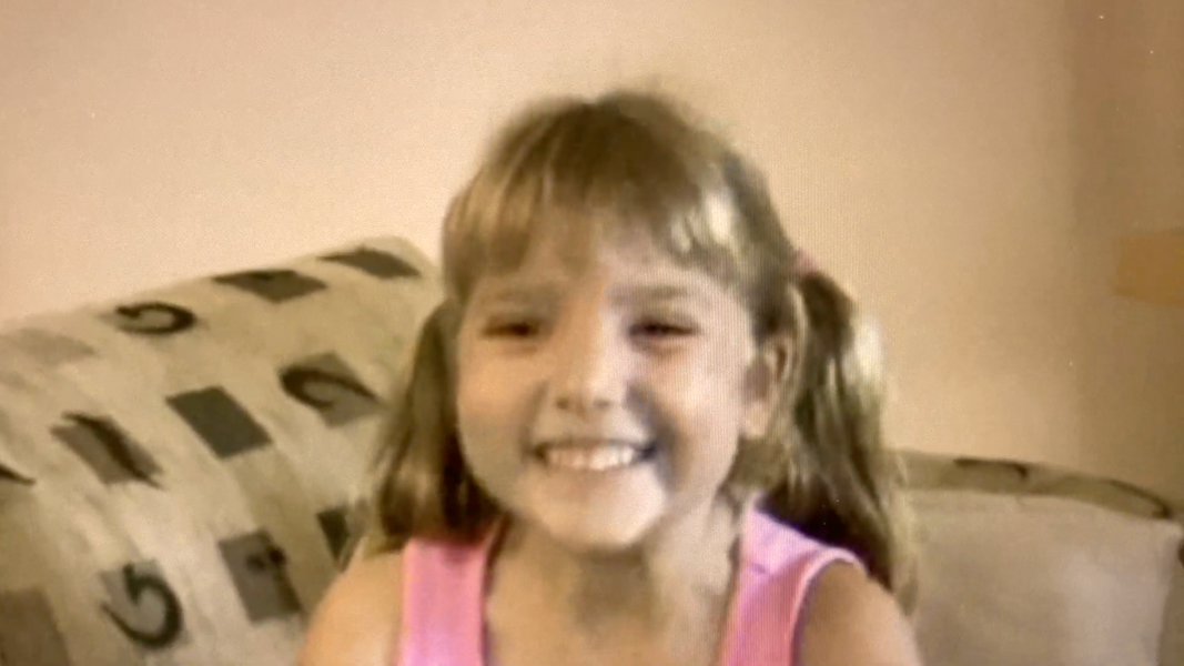 Photo of Rachael from her childhood, smiling on a couch
