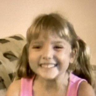 Photo of Rachael from her childhood, smiling on a couch