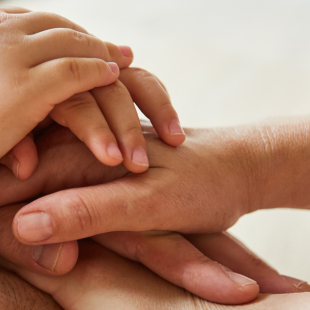 Three sets of hands stacked on top of each other, with adult and child hands layered together, representing three generations.